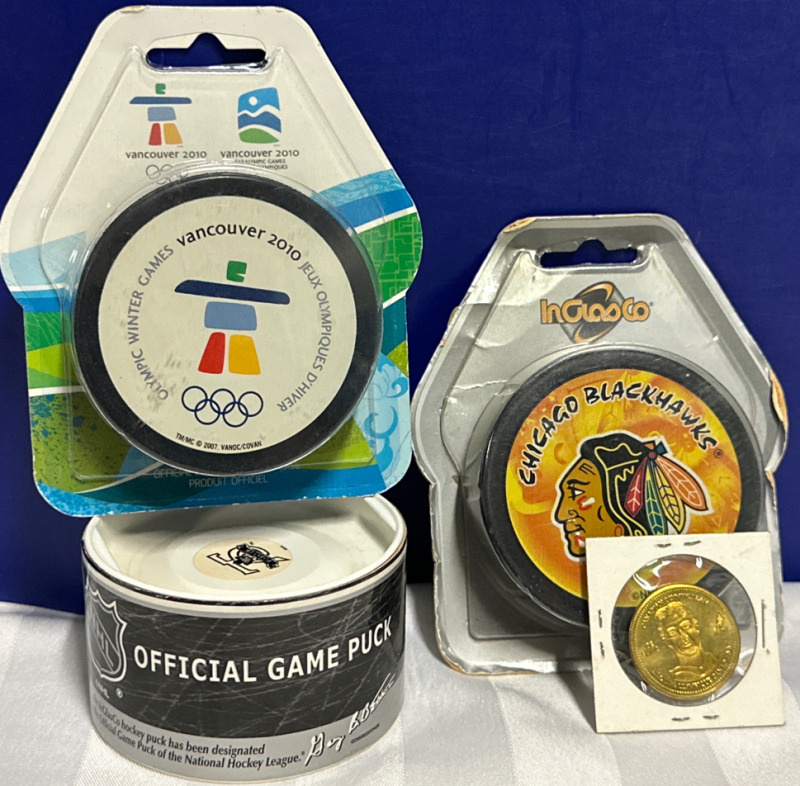 4 Piece NHL Collectors Lot Including NHL Official Fame Puck Vancouver 2010 Olympic Puck Chicago Blackhawks Puck and 2007 Olympic Joe Sakic Token